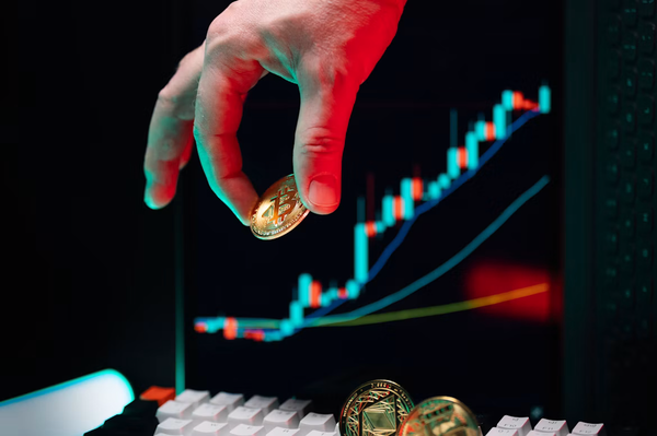 Photographie d'une main attrapant des pièces symbolisant diverses cryptomonnaies